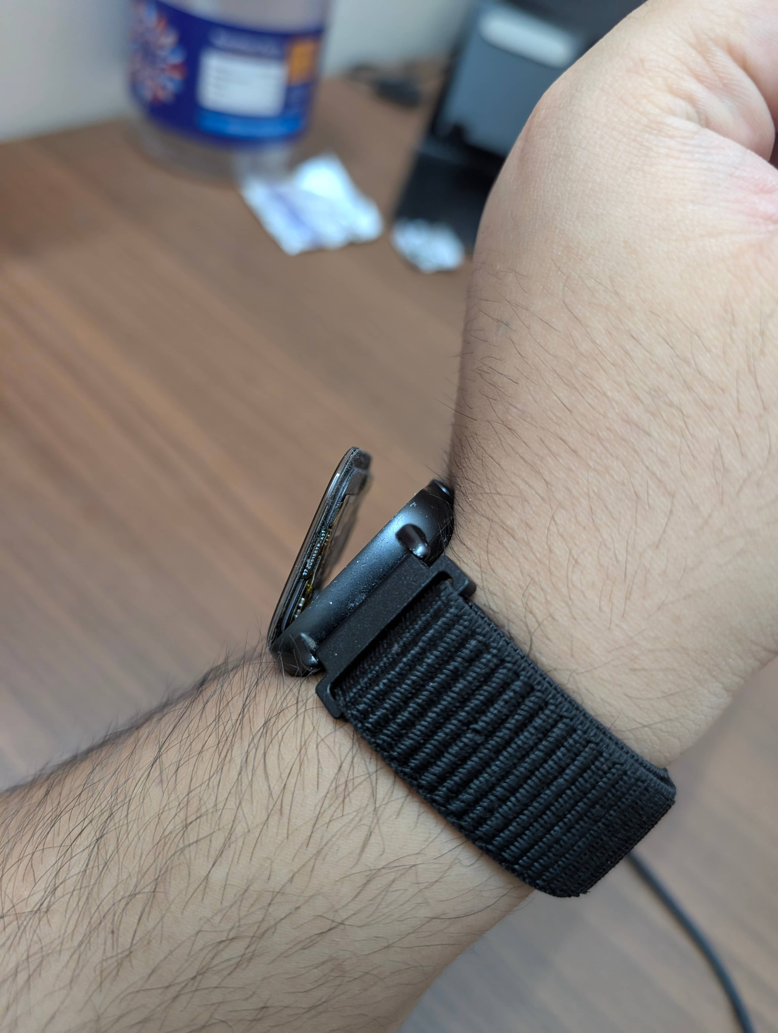 A picture of the aforementioned watch on my arm, with its display precariously detached from the rest of the body and only attached on the left side. The watch is kind of scuffed and filthy.